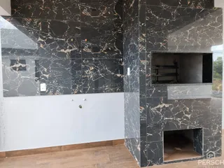 Parede interna com revestimento de mármore escuro e piso de cerâmica em um ambiente residencial.