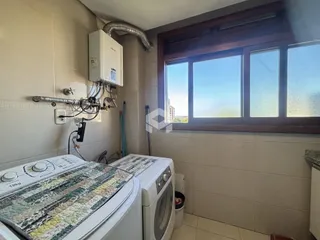 Foto de uma área de serviço com máquina de lavar e janela.