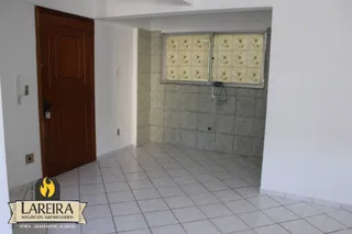 Interior de um corredor com piso de cerâmica e porta de madeira.