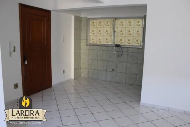 Interior de um corredor com piso de cerâmica e porta de madeira.