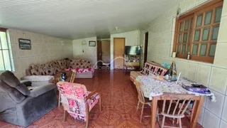 Sala de estar com sofá e cadeiras decorativas em um imóvel com piso de madeira.
