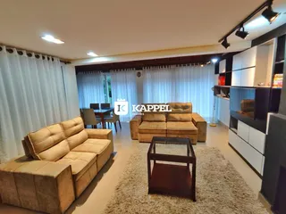 Sala de estar com sofá grande e cortinas brancas.