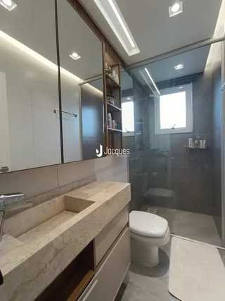 Banheiro moderno com bancada de mármore e box de vidro.