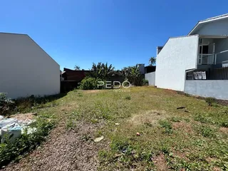 Vista externa de um terreno com grama e paredes brancas.