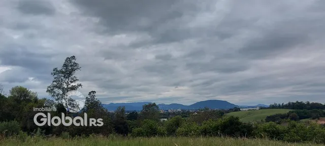 Paisagem de campo com montanhas ao fundo sob um céu nublado.