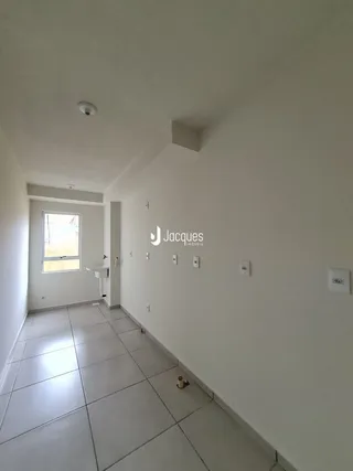 Corredor interno de uma residência com paredes brancas e piso de cerâmica.