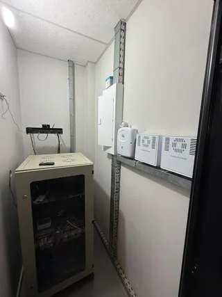 Interior de um cômodo com paredes brancas e tubulações visíveis.