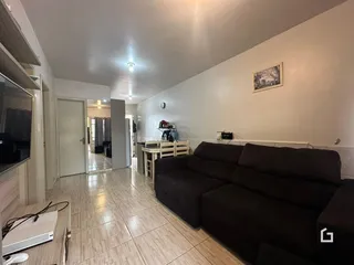 Interior de uma sala de estar com piso de cerâmica e sofá escuro.
