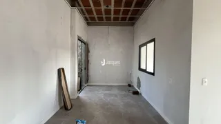 Interior de um espaço com paredes brancas e teto de estrutura exposta.