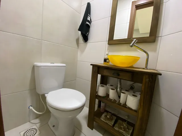 Foto de um banheiro com vaso sanitário e bancada de madeira.