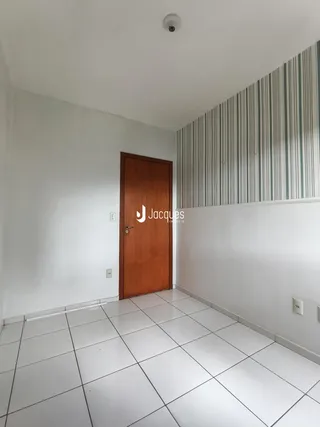 Hall de entrada com piso de cerâmica branca e porta de madeira.