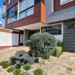 Foto de uma área externa com vegetação densa e piso de ladrilhos em uma residência.