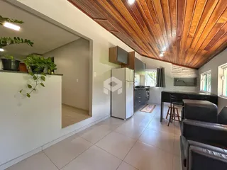 Interior de uma sala de estar com piso de cerâmica e teto de madeira em um imóvel em Lajeado.