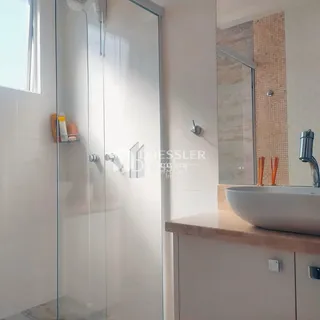 Foto de um banheiro com box de vidro e pia.