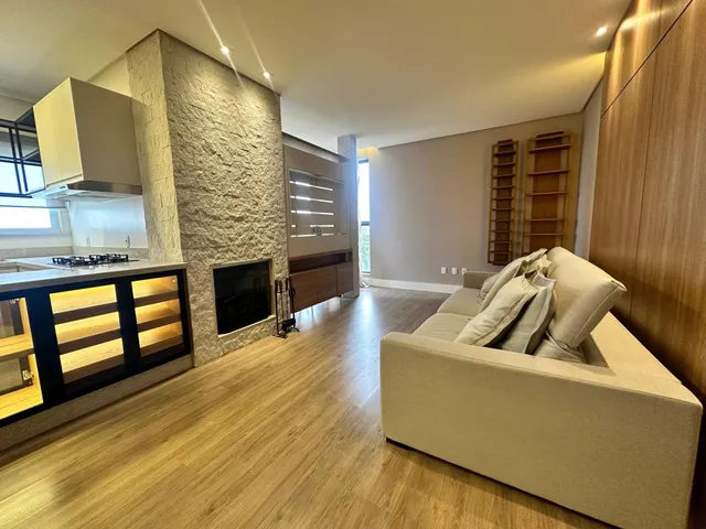 Sala de estar com piso de madeira e lareira em um apartamento em Lajeado.