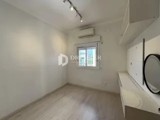 Quarto interno com piso de madeira clara e paredes brancas.