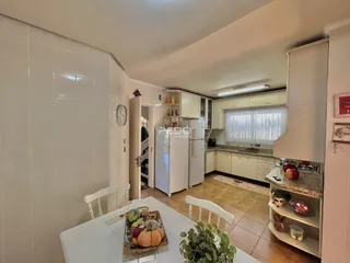 Uma cozinha iluminada com armários brancos e piso de cerâmica.