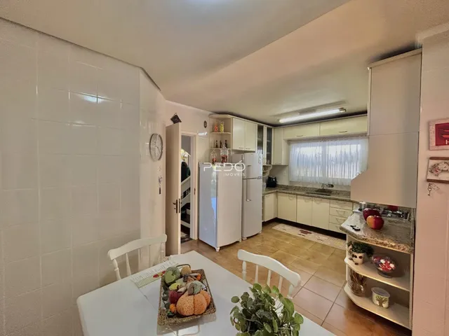 Uma cozinha iluminada com armários brancos e piso de cerâmica.