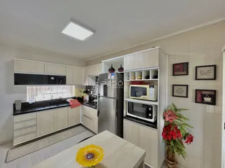 Vista da cozinha moderna com armários brancos e eletrodomésticos em Lajeado.