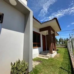 Fachada externa de uma residência com paredes brancas e telhado de telha.