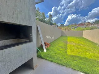 Vista externa de um quintal com gramado e muro de contenção.