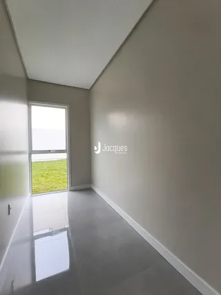 Vista de uma janela de um cômodo interno com gramado verde ao exterior.