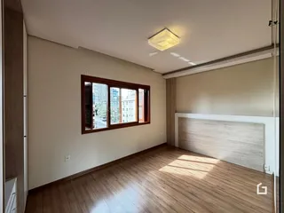 Quarto com piso de madeira e janela para a cidade.