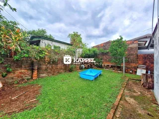 Vista externa mostrando um gramado e muro de tijolos em uma propriedade.