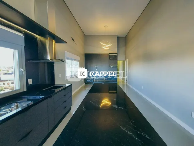 Vista interna de uma cozinha moderna com armários pretos e piso escuro.