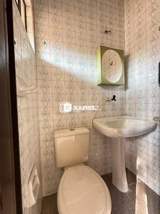 Foto interna de um banheiro com azulejos brancos nas paredes.