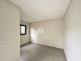 Corredor interno com paredes brancas e piso cinza.