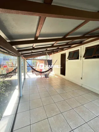 Uma área coberta com piso de cerâmica e estrutura de madeira é visível na propriedade.