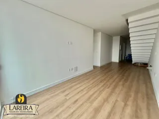 Vista de um corredor interno com piso de madeira clara.