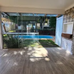 Sala de estar com grande porta de vidro que dá acesso a uma área externa com piscina.