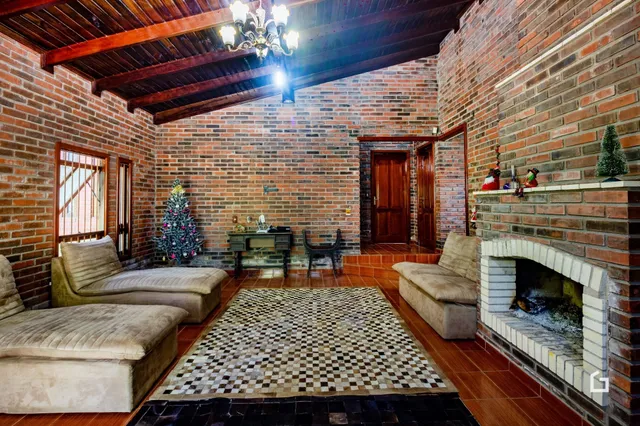 Sala de estar com paredes de tijolo aparente e lareira em casa em Lajeado.