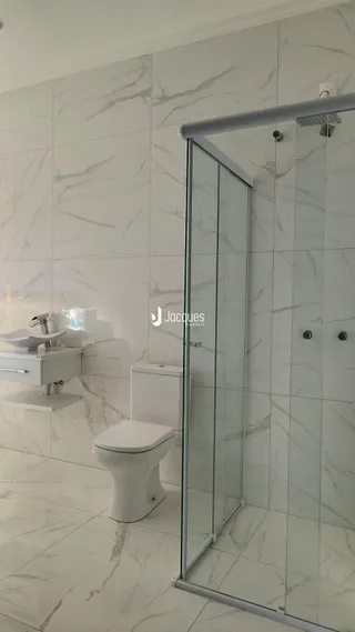 Foto de um banheiro com revestimento em mármore branco e box de vidro.
