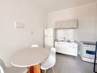 Esta é uma foto de uma cozinha com armários brancos e uma mesa de jantar.