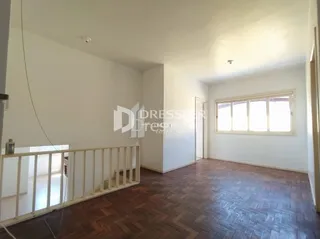 Interior de um ambiente com piso de madeira e paredes brancas.