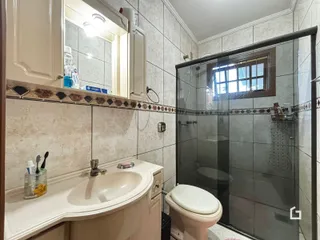Foto interna de um banheiro com revestimento de azulejos brancos.