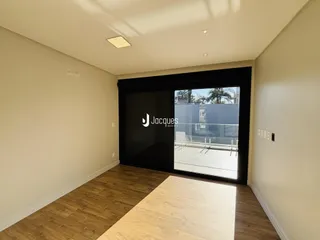 Vista de um corredor interno com piso de madeira e porta de vidro.