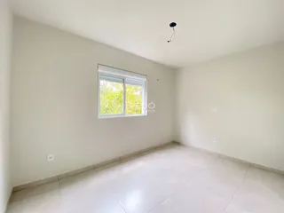 Uma sala interna com paredes brancas e piso de cerâmica clara.