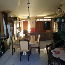 Foto de uma sala de jantar com mesa de madeira e sofá no fundo.