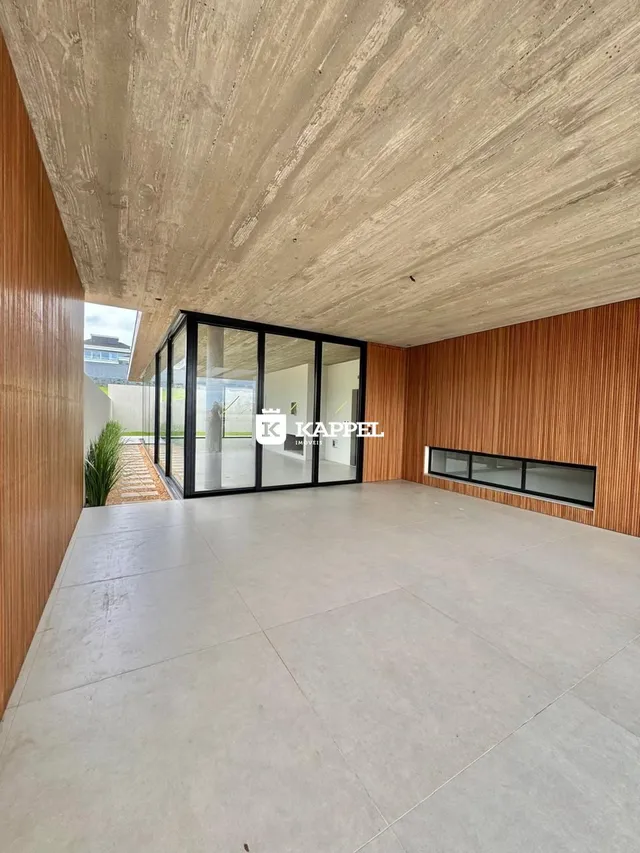 Ambiente interno amplo com piso claro e divisória de vidro.