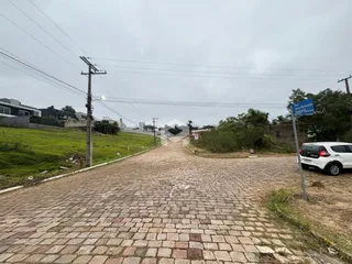 Uma estrada pavimentada com pedras leva a uma área verde.