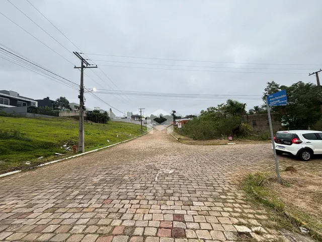 Uma estrada pavimentada com pedras leva a uma área verde.