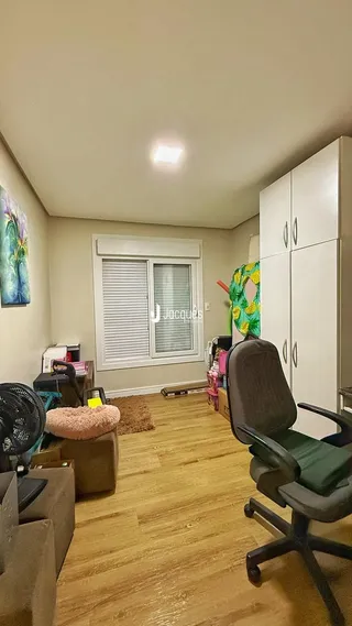 Ambiente interno de uma sala com piso de madeira clara e armários brancos.