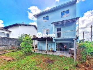 Foto da fachada de uma casa azul em Lajeado, Brasil com jardim na frente.
