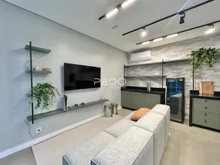 Sala de estar moderna com sofá e televisão em um ambiente claro.