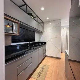 Foto interna de uma cozinha com armários escuros e bancada escura.