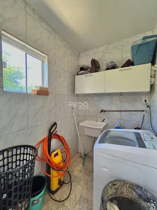 Foto de um ambiente interno com azulejos brancos, pia e máquina de lavar roupa.